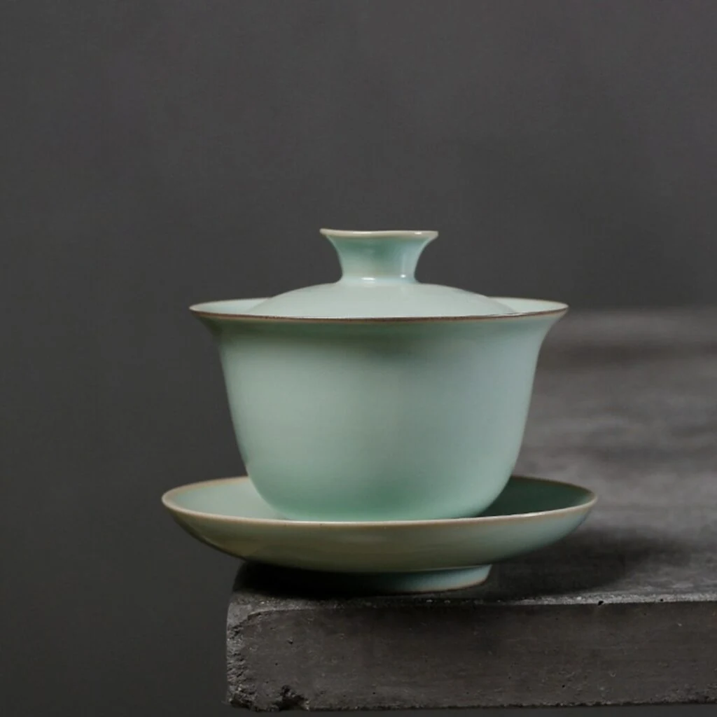 Gongfu tea steeping ritual with handcrafted celadon gaiwan