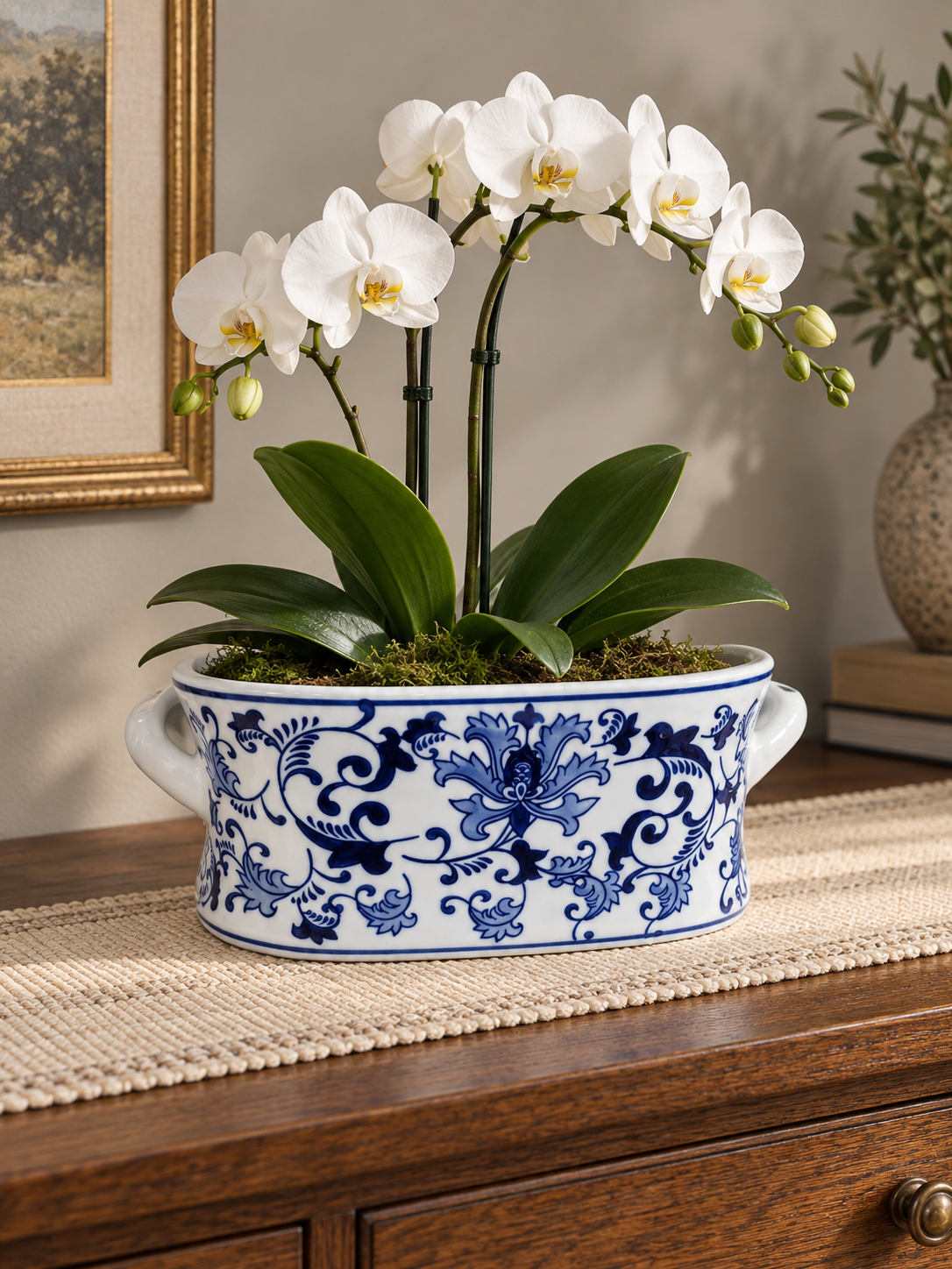 Blue and white oval planter styled with white orchids on a light table runner