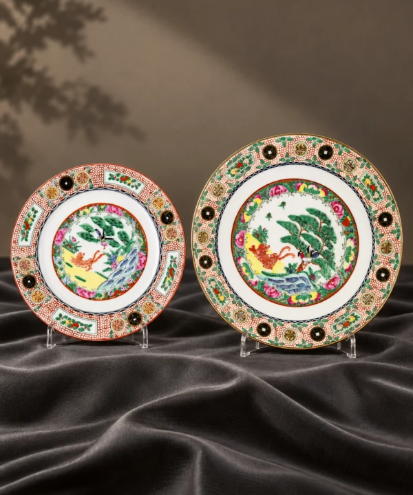 Pair of colorful decorative porcelain plates displayed on dark fabric
