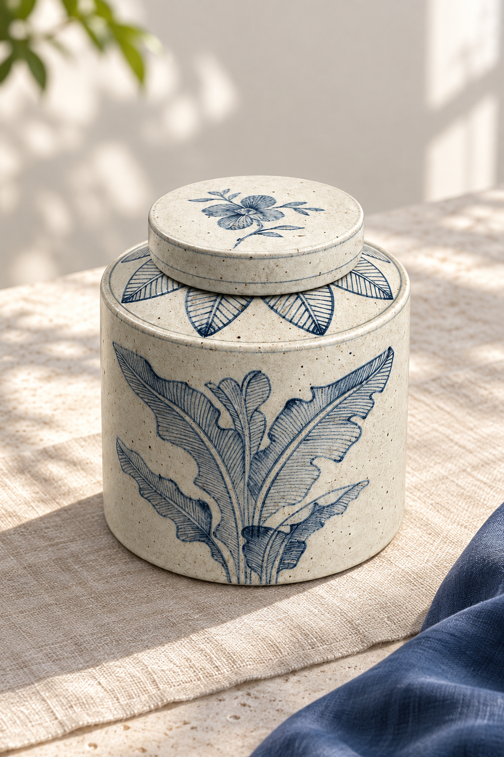 Blue leaf-pattern ceramic jar with a flat lid in natural light