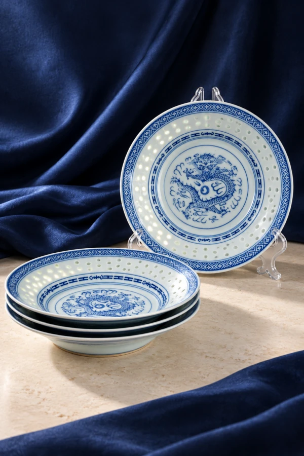Blue and white dragon-pattern plates and shallow bowls against blue fabric