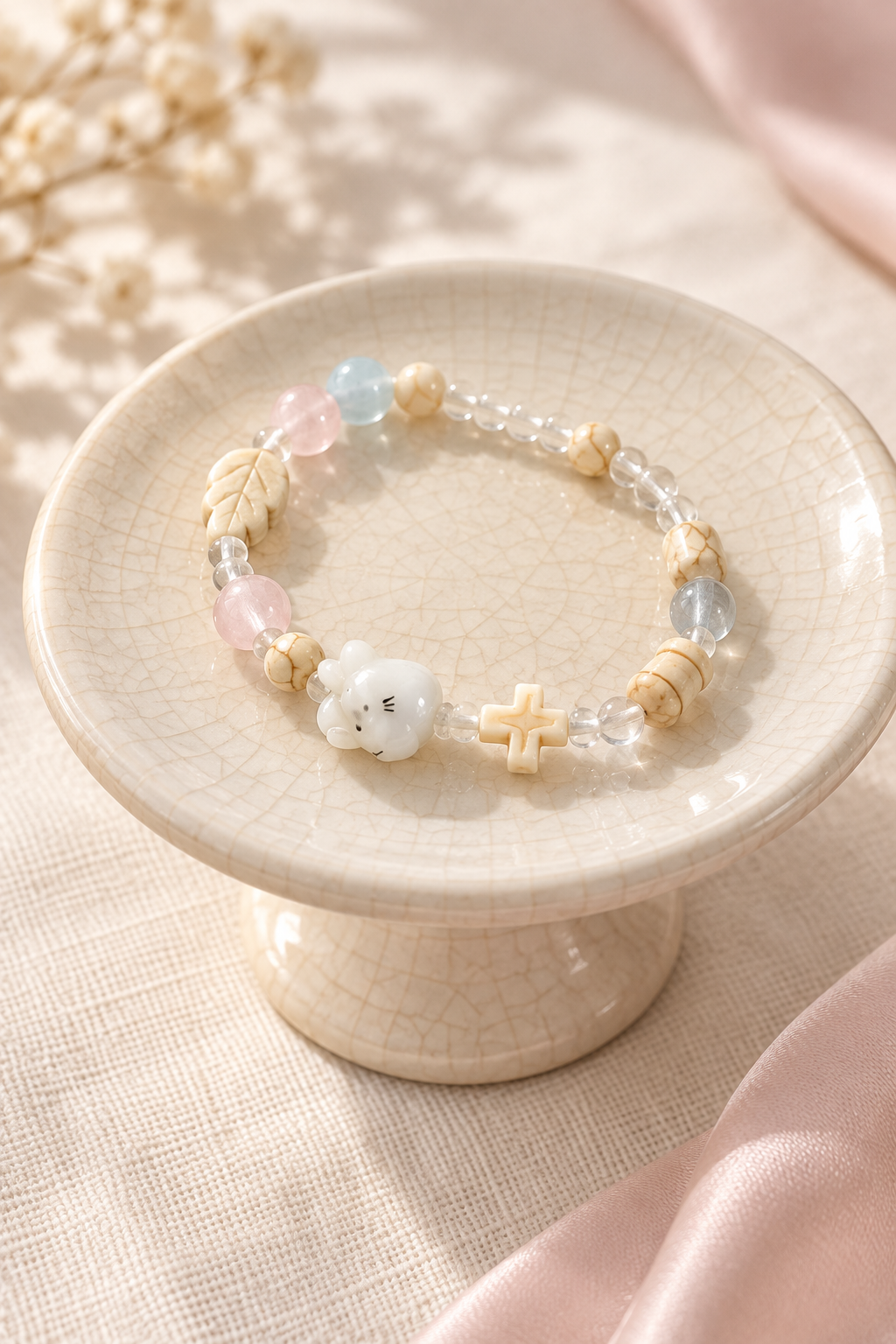 Pastel cat bracelet displayed on a raised cream ceramic dish