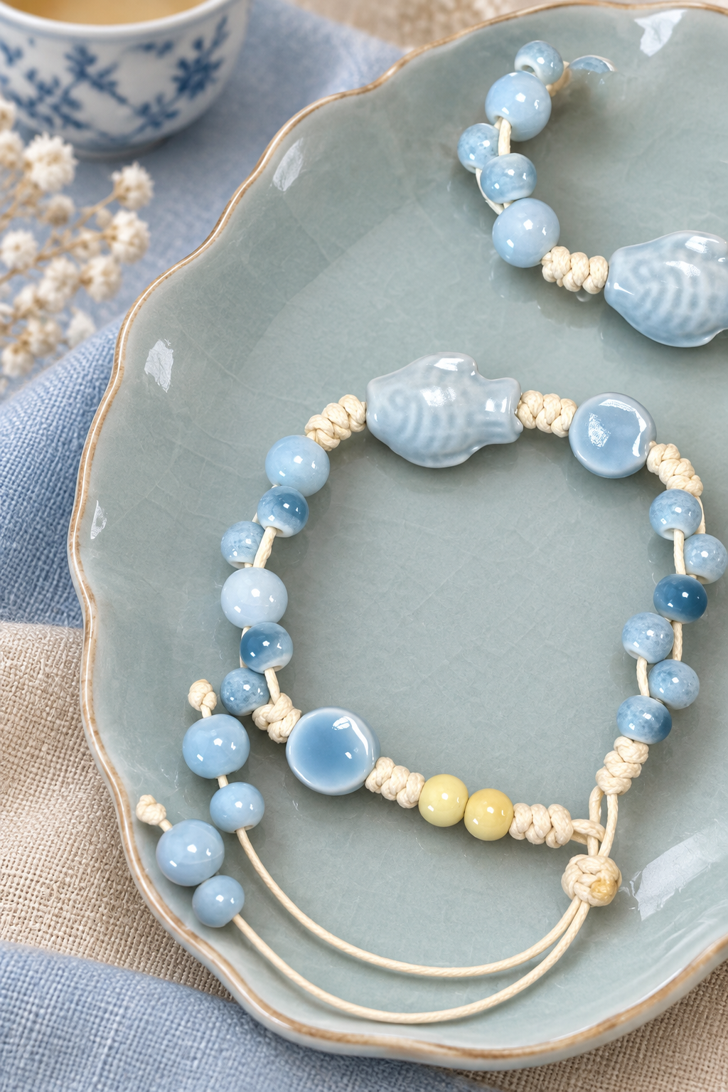 Close-up of a pale blue ceramic fish bead and matching round bracelet beads