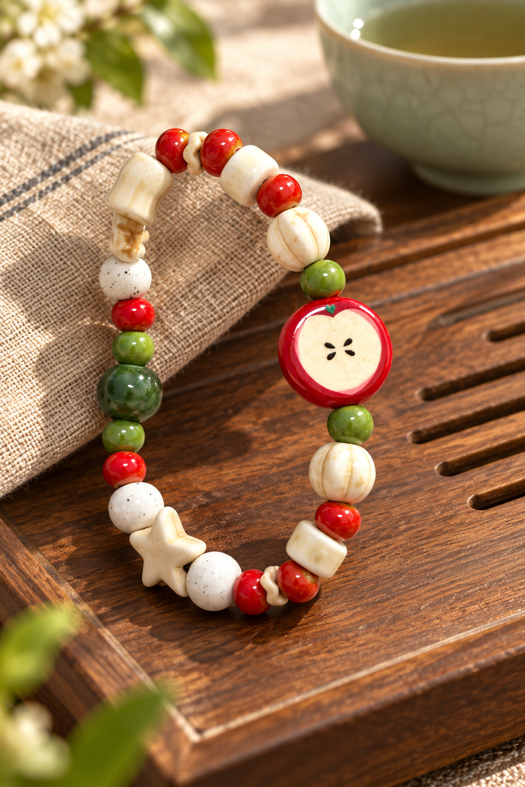 Red apple ceramic bracelet with cream and green beads on a wooden table