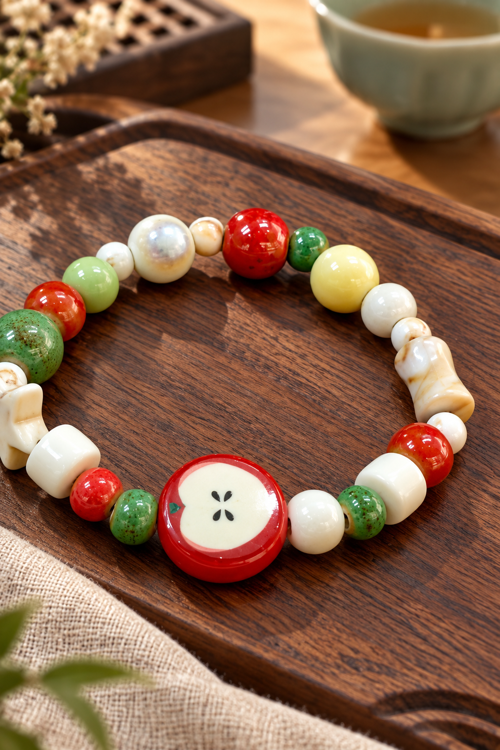 Close-up of a red apple-slice bead and multicolored ceramic bracelet beads