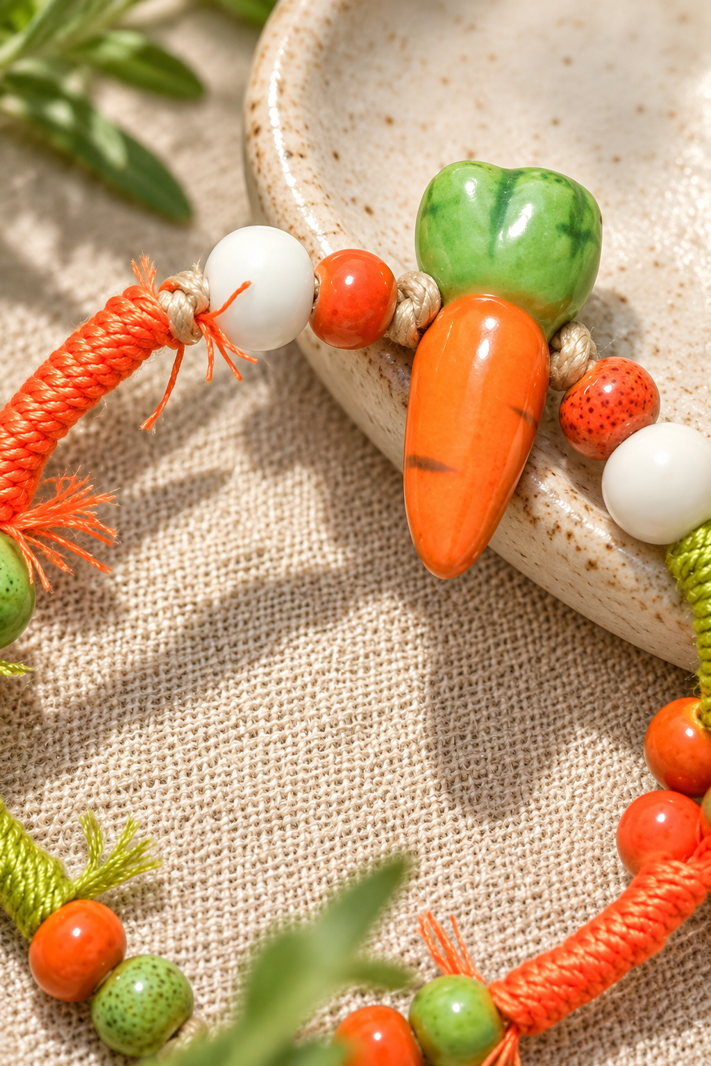 Close-up of an orange ceramic carrot bead and knotted bracelet cords